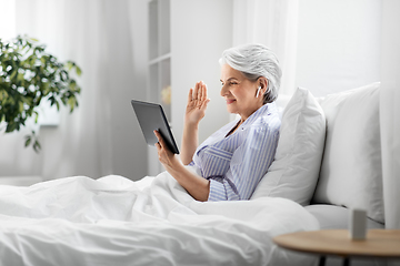 Image showing old woman with tablet pc having video call in bed