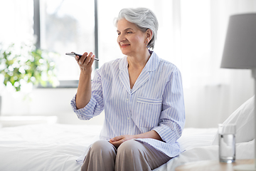 Image showing happy senior woman recording voice on smartphone