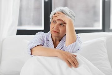 Image showing senior woman with headache sitting in bed at home