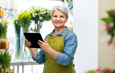 Image showing happy senior woman in garden apron with tablet pc