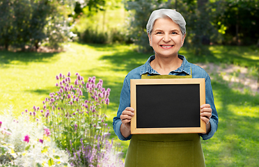 Image showing happy senior woman in garden apron with chalkboard