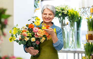 Image showing smiling senior woman in garden apron with flowers