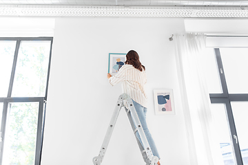 Image showing woman on ladder decorating home with art