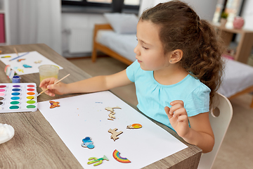 Image showing little girl painting wooden items at home