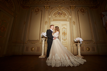 Image showing Charming wedding couple in interior in Baroque style is hugging each other on great royal palace