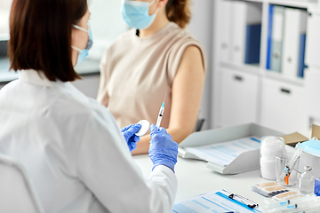 Image showing female doctor with syringe vaccinating patient