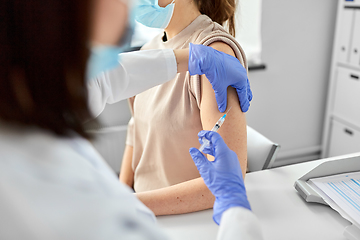 Image showing female doctor with syringe vaccinating patient