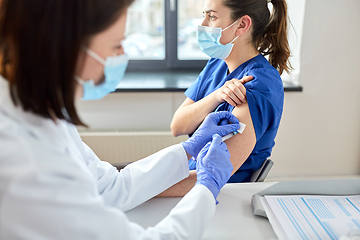 Image showing doctor with syringe vaccinating medical worker