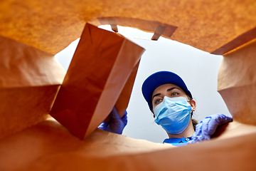 Image showing delivery girl in gloves and mask with food in bag