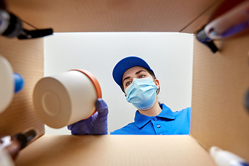 Image showing woman in mask packing parcel box with cosmetics