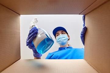 Image showing woman in mask packing cleaning supplies in box