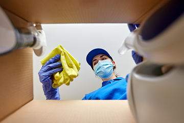 Image showing woman in mask packing cleaning supplies in box