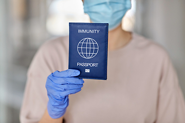 Image showing woman in mask and gloves holding immunity passport