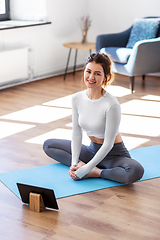Image showing young woman with tablet pc doing yoga at home