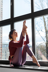 Image showing woman doing yoga exercise on window sill at studio