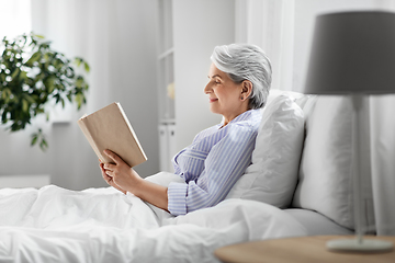 Image showing senior woman reading book in bed at home bedroom