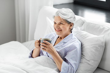 Image showing old woman with cup of coffee in bed at home