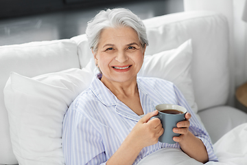 Image showing old woman with cup of coffee in bed at home