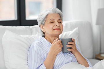 Image showing old woman with cup of coffee in bed at home