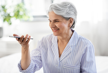 Image showing happy senior woman recording voice on smartphone