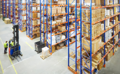 Image showing Blur warehouse background. Above view of warehouse workers moving goods and counting stock in aisle between rows of tall shelves full of packed boxes