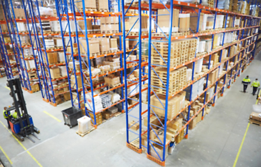 Image showing Blur warehouse background. Above view of warehouse workers moving goods and counting stock in aisle between rows of tall shelves full of packed boxes