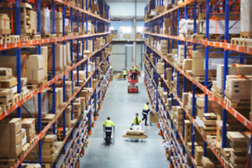 Image showing Blur warehouse background. Above view of warehouse workers moving goods and counting stock in aisle between rows of tall shelves full of packed boxes