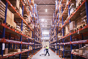 Image showing Male warehouse worker pulling a pallet truck.