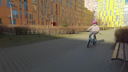 Image showing Girl rides a bike through city streets. Beautiful girl rides bicycle in park on street, sunny day. A teenager rides bicycle in park. Health and sport concept.