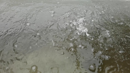 Image showing Rain water drops falling into big puddle on asphalt, flooding the street. Road floods due to the heavy rain in wet season. Raindrops falling down onto submerged road.