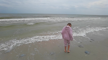 Image showing Little kid girl plays on beach shallow water line summer rest during vacations