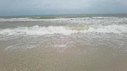 Image showing Big tide waves with foam and splashes are crushing beach in slow motion.