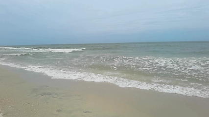 Image showing Big tide waves with foam and splashes are crushing beach in slow motion.