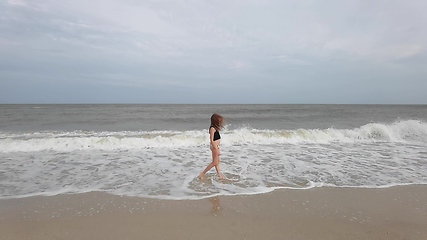 Image showing Little kid girl plays on beach shallow water line summer rest during vacations