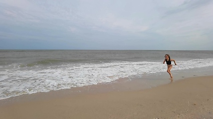 Image showing Little kid girl plays on beach shallow water line summer rest during vacations