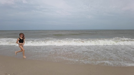 Image showing Little kid girl plays on beach shallow water line summer rest during vacations