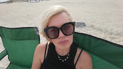 Image showing Slow motion portrait face of beautiful young woman with short blonde hair looking at camera sitting on sea beach