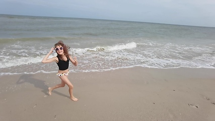 Image showing Little kid girl plays on beach shallow water line summer rest during vacations