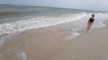 Image showing Little kid girl plays on beach shallow water line summer rest during vacations