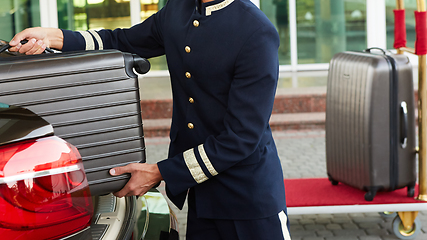 Image showing Bellboy taking baggage of guest from thee car to his room