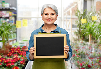 Image showing happy senior woman in garden apron with chalkboard