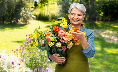 Image showing smiling senior woman in garden apron with flowers