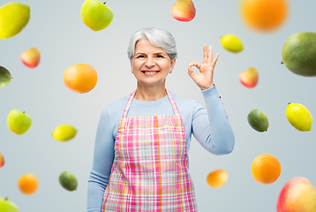 Image showing smiling senior woman in apron showing ok gesture