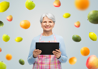 Image showing smiling senior woman in apron with tablet computer