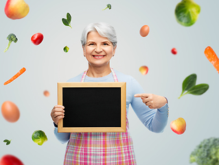 Image showing smiling senior woman in apron with chalkboard