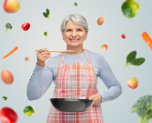 Image showing smiling senior woman in apron with frying pan