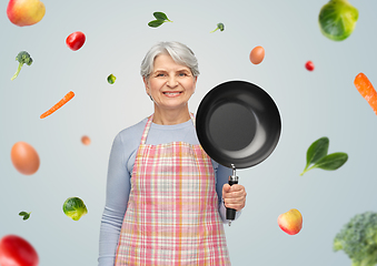 Image showing smiling senior woman in apron with frying pan