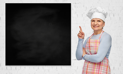 Image showing senior woman or chef pointing finger to chalkboard