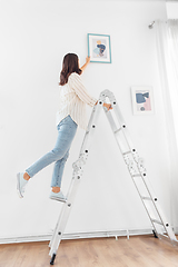 Image showing woman on ladder decorating home with art