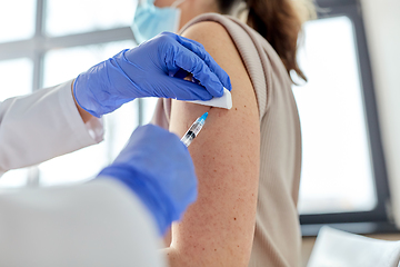 Image showing female doctor with syringe vaccinating patient